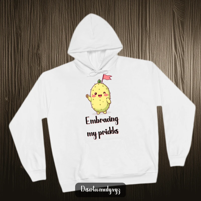 Funny hoodie featuring a cheerful prickly pear cactus with shy blushing cheeks, waving a tiny flag in a warm, friendly gesture.